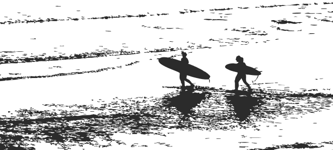 Two surfers carrying their boards along the shoreline